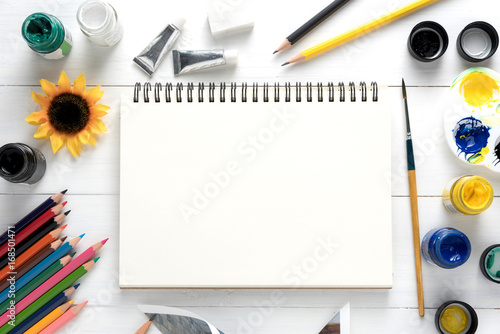 Notepad, and art supplies on white table.