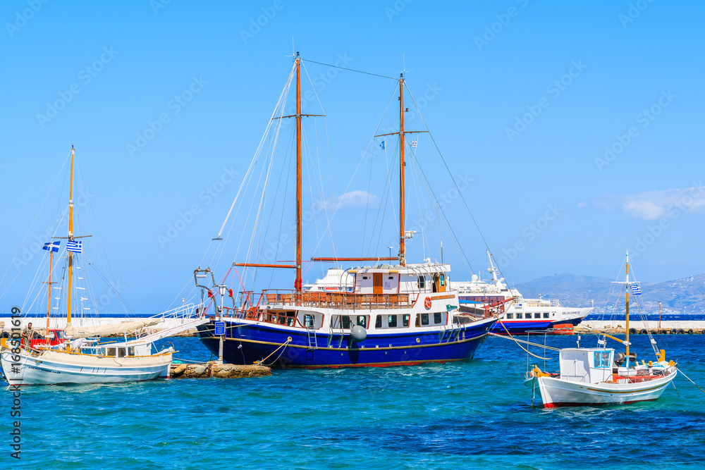 MYKONOS PORT, GREECE - MAY 17, 2016:Sailing and fishing boats on blue sea in Mykonos port, Mykonos island, Greece.