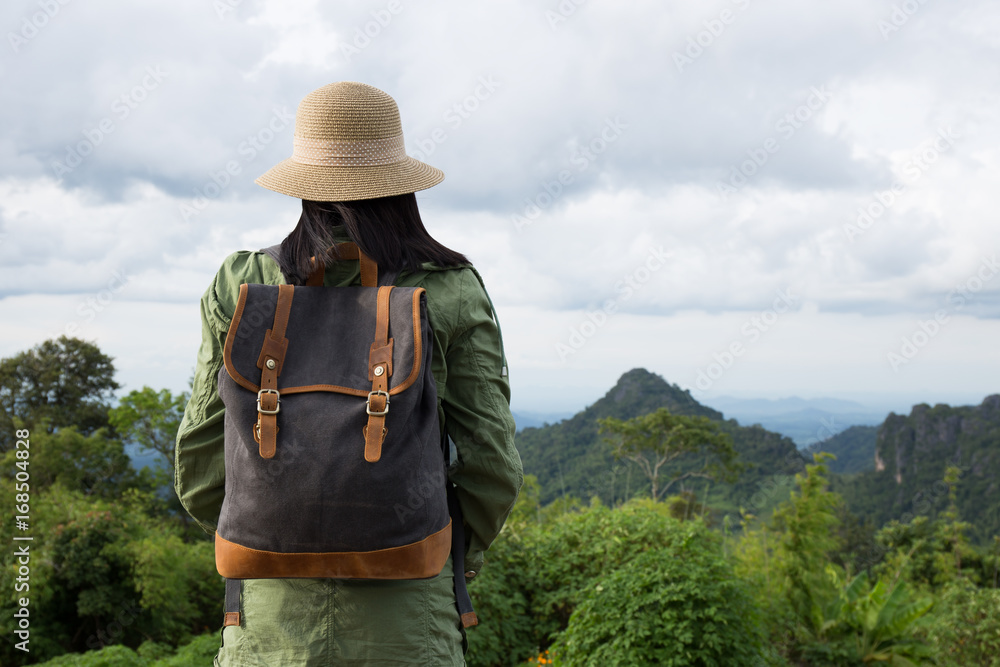 Hipster young woman with backpack enjoying. Tourist traveler on mountain background