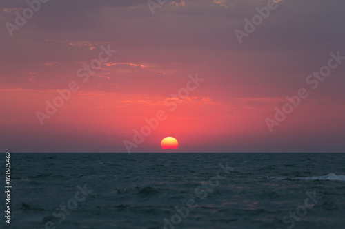 Dawn over the sea, the red sun rises above the horizon