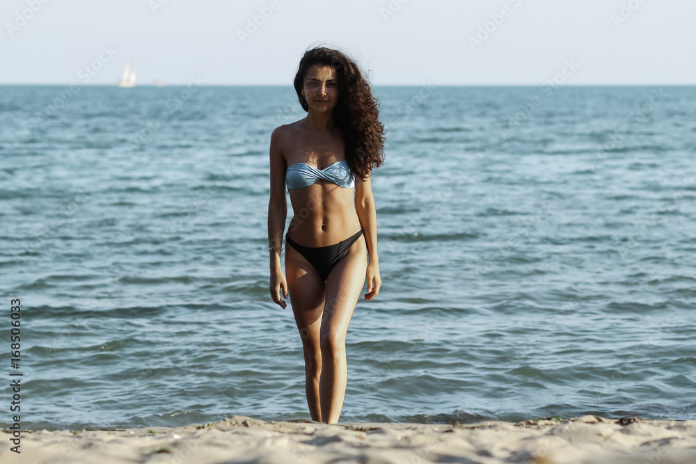 Obraz premium Hight fashion colors,Glamour Portrait of pretty beautiful fashion woman in bikini posing in summer near the sea and blue sky in sunshine,tropic island girl on vacation