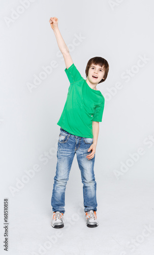 Happy boy with hand up celebrating win on white studio background