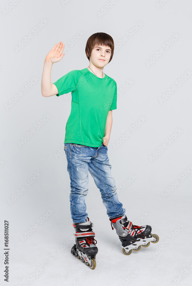 Happy boy ready to roller skate and waving his hand at studio. Happy boy ready to roller skate and waving his hand at studio.