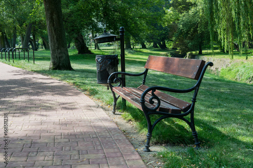 Wooden bench in a green park next to a foot path