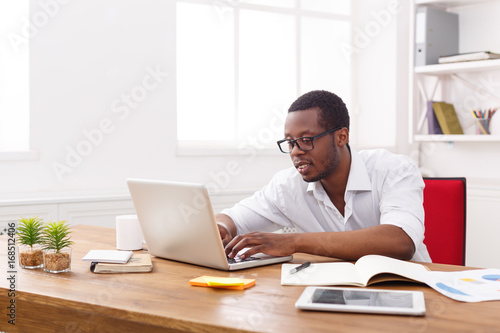 Black businessman in white office, work with laptop
