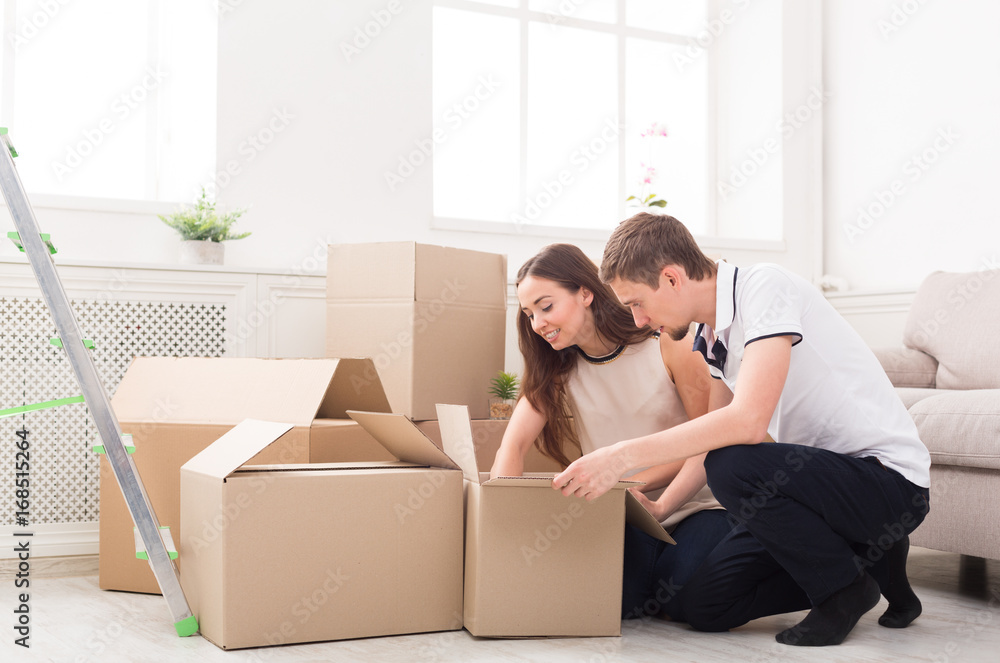 Young couple unpacking moving boxes Young couple unpacking moving boxes