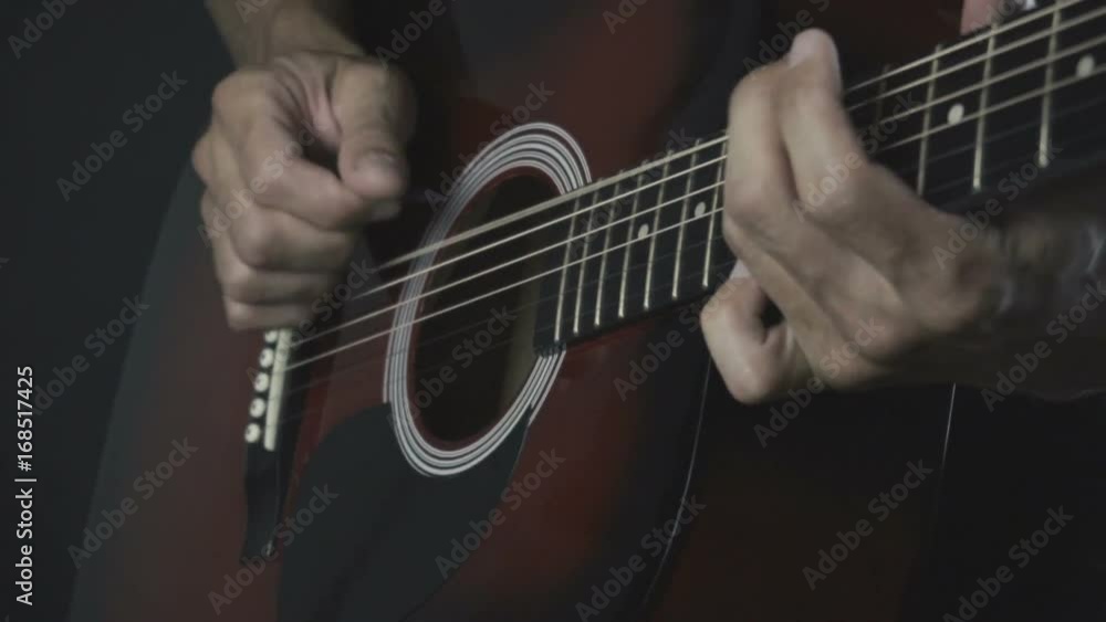 Man playing acoustic guitar on black background with fingers in slow motion Man playing acoustic guitar on black background with fingers in slow motion