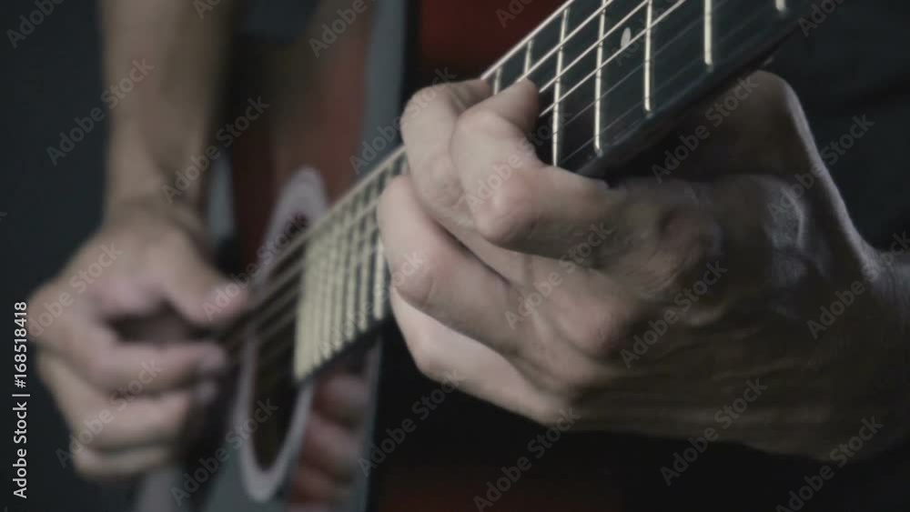 Man playing acoustic guitar on black background with fingers in slow motion Man playing acoustic guitar on black background with fingers in slow motion