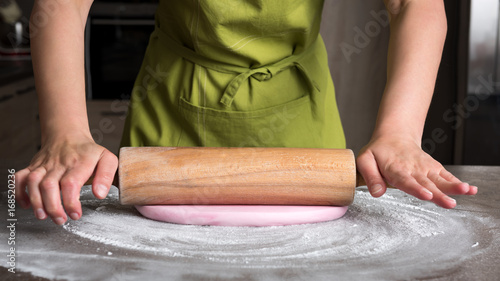Tableau sur toile Woman using rolling pin preparing pink fondant for cake decorating, hands detail
