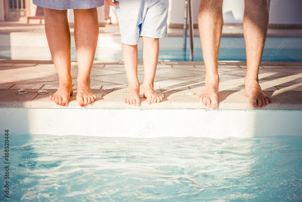 feet of a young family near the pool. Feet of mother, the father and the child