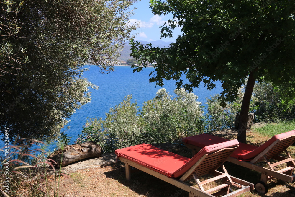 Sunbeds with with a great view looking through trees onto the bays at fethiye in turkey, 2017 Sunbeds with with a great view looking through trees onto the bays at fethiye in turkey, 2017