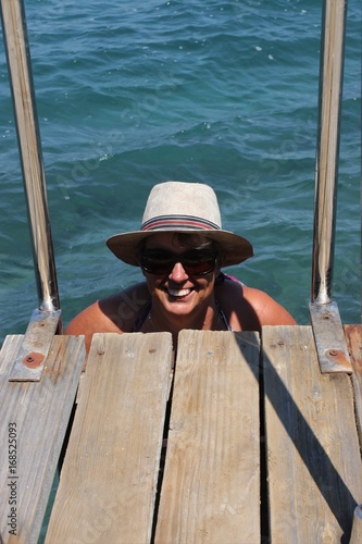 A  mature english lady getting out of the sea using ladders on the jetty while on vacation in turkey 2017