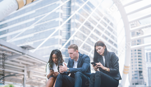 Group of young people use their phones in city