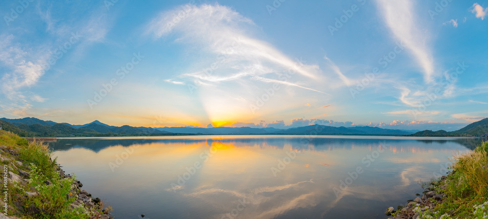 Dramatic view and magic sunbeam at sunset, mountain background. Tranquil panorama landscape of Yang Choom Reservoir, Kui Buri, Prachuap Khirikhan, Thailand.