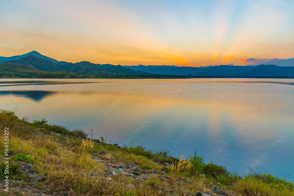 Dramatic view and magic sunbeam at sunset, mountain background. Tranquil panorama landscape of Yang Choom Reservoir, Kui Buri, Prachuap Khirikhan, Thailand.
