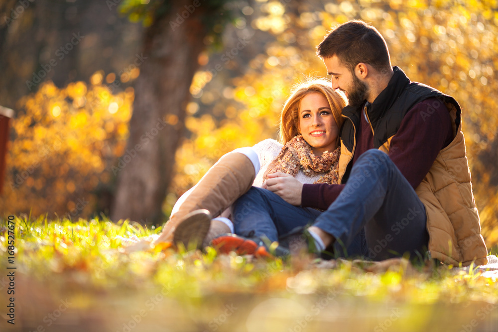 Fototapeta premium Love couple sitting under a tree in the colorful spring garden at sunset