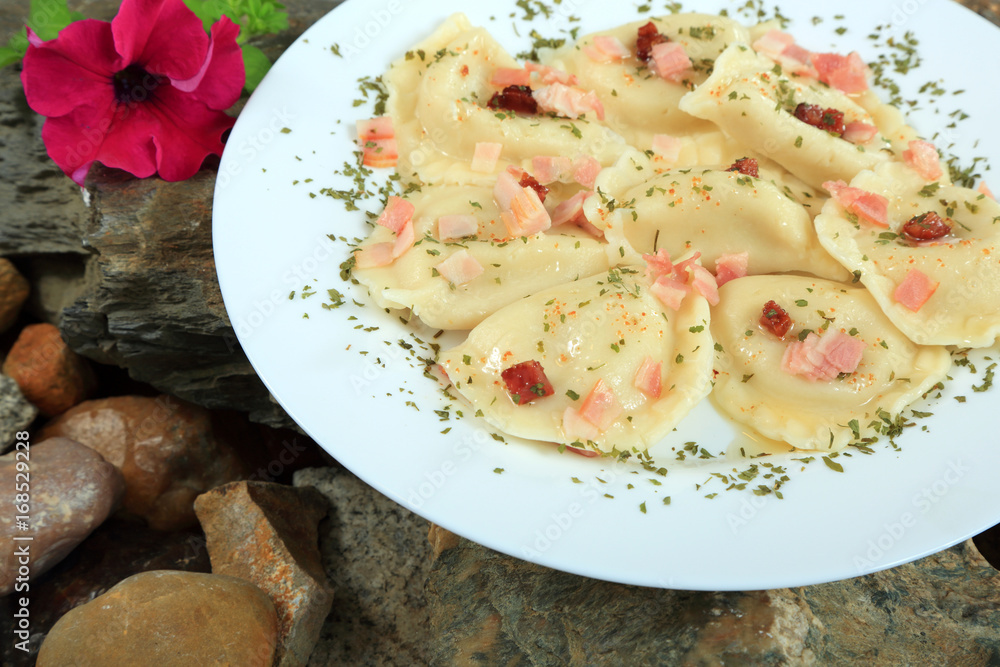 Pierogi ze skwarkami i pietruszką na białym talerzu, na skałach. Pierogi ze skwarkami i pietruszką na białym talerzu, na skałach.