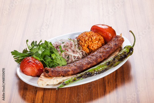 Turkish kebab served with yoghurt and vegetables on wooden table