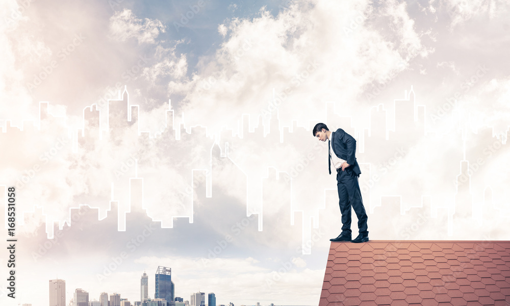 Businessman looking down from roof and modern cityscape at backg Businessman looking down from roof and modern cityscape at backg