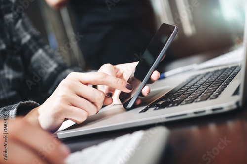 Close Up view of businesswoman working on modern smartphone and laptop. Closeup view of female hands typing on phone