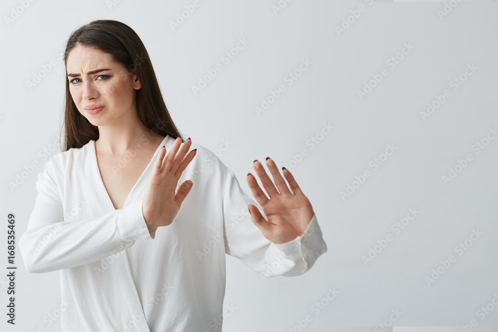 Displeased young beautiful woman showing stop stretching from camera over white background. Displeased young beautiful woman showing stop stretching from camera over white background.