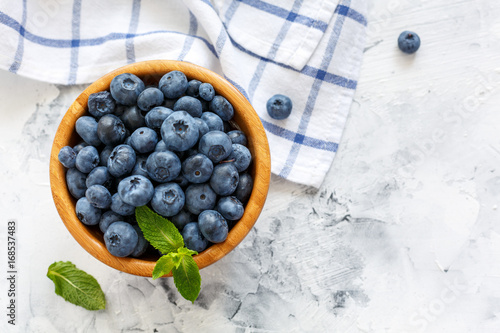 Ripe blueberries and mint in a wooden bowl.