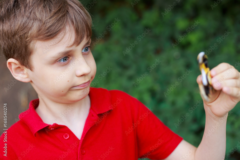 Boy playing with fidget spinner, close up. Childhood, gadgets, entertainment concept Boy playing with fidget spinner, close up. Childhood, gadgets, entertainment concept