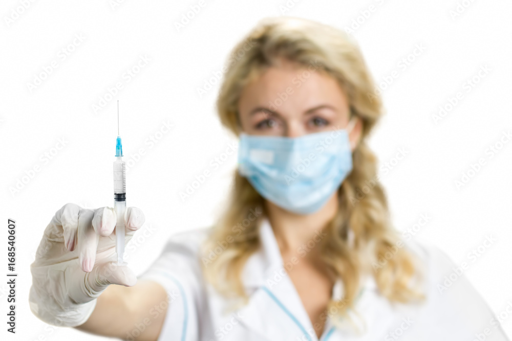 Close up of syringe in nurse hand. Young female doctor or nurse in surgical mask holding an injection in her outstretched hand, white background. Close up of syringe in nurse hand. Young female doctor or nurse in surgical mask holding an injection in her outstretched hand, white background.