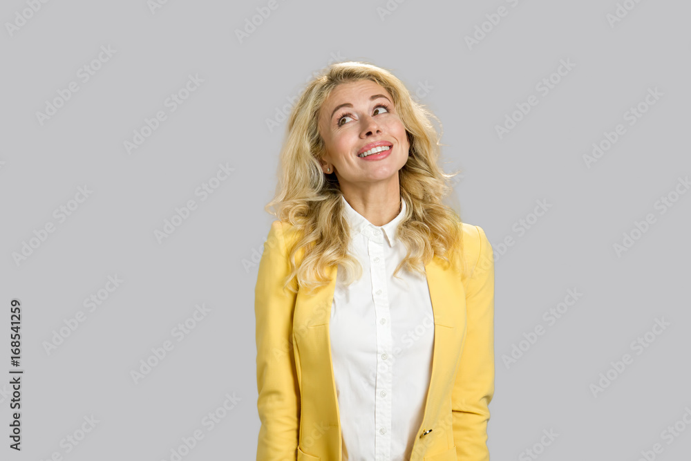 Smiling young woman looking upwards. Portrait of smiling young lady in formal wear isolated on grey background. Smiling young woman looking upwards. Portrait of smiling young lady in formal wear isolated on grey background.