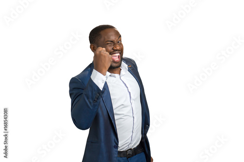Succesful businessman with raised fist. Cheerful black man in formal wear raised his fist as champion, side photo.