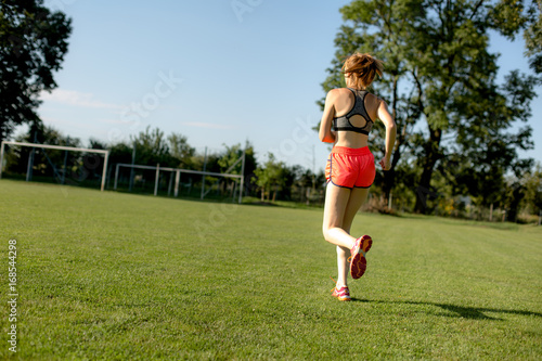 Young girl is running on green field, training concept