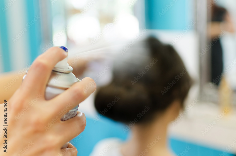 Hairdresser using hairspray on client's hair Hairdresser using hairspray on client's hair