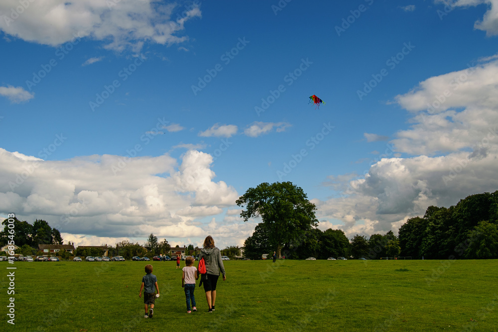 Obraz premium Young woman with children and a kite in blue sky.