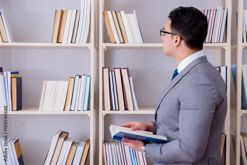 Businessman student reading a book studying in library Businessman student reading a book studying in library