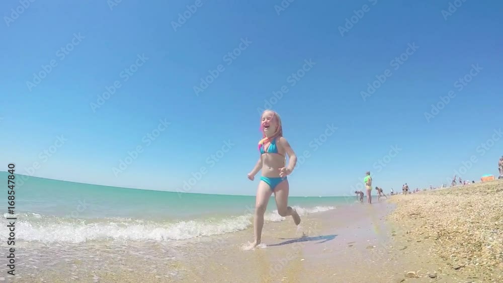 A pretty girl runs along the beach, enjoys bathing in the sea. The concept of getting pleasure from summer holidays, joy in a sunny summer day. A pretty girl runs along the beach, enjoys bathing in the sea. The concept of getting pleasure from summer holidays, joy in a sunny summer day.