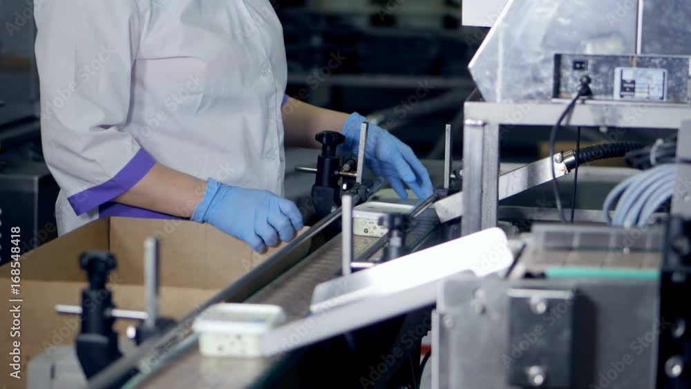 Female worker taking packaged cheese from conveyor. Female worker taking packaged cheese from conveyor.