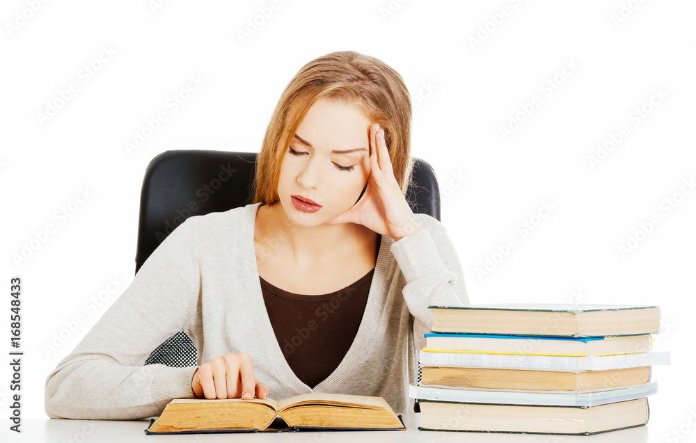 Beautiful casual student woman sitting by stack of books and lea Beautiful casual student woman sitting by stack of books and lea