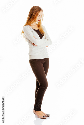 Beautiful woman is standing, lookis sad, with her hands crossed.