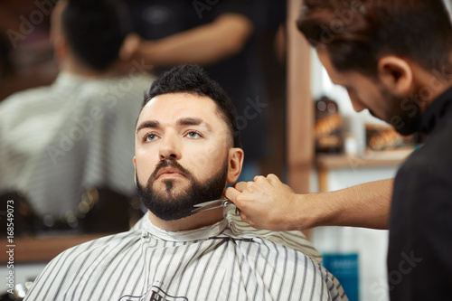 Barber grooming man in chair