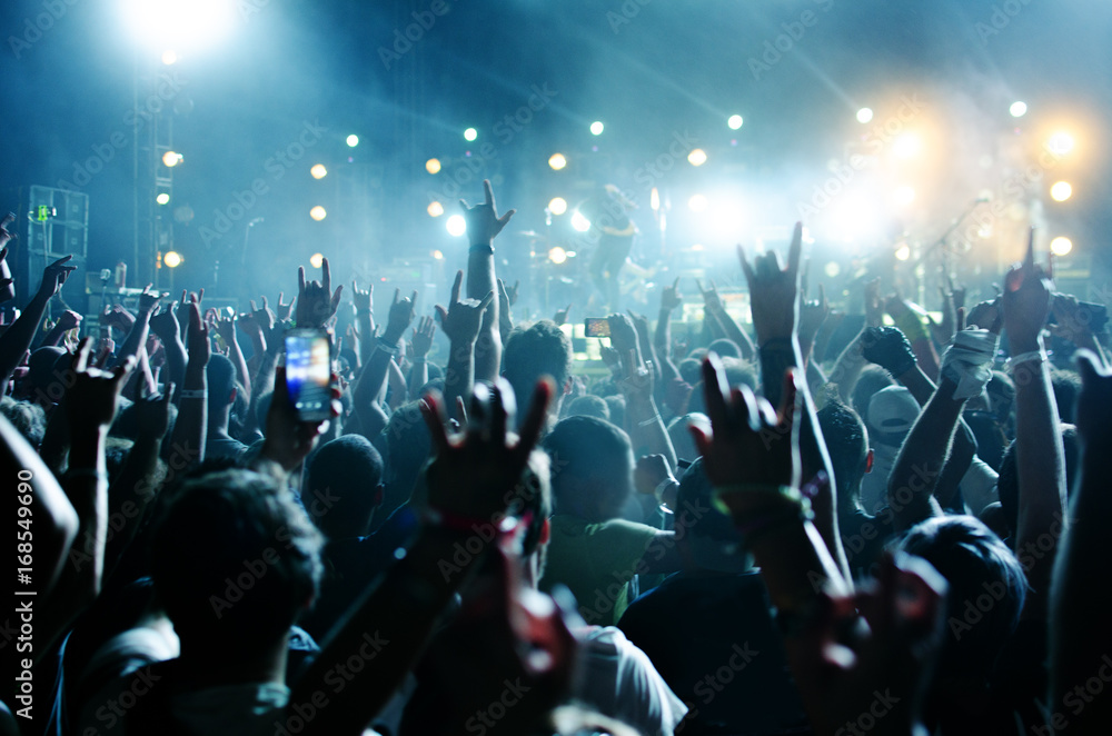 silhouettes of concert crowd in front of bright stage lights