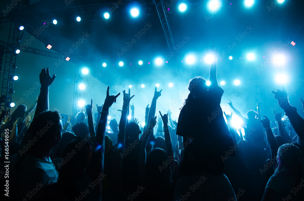 Concert crowd in front of bright stage lights. Silhouettes of people.