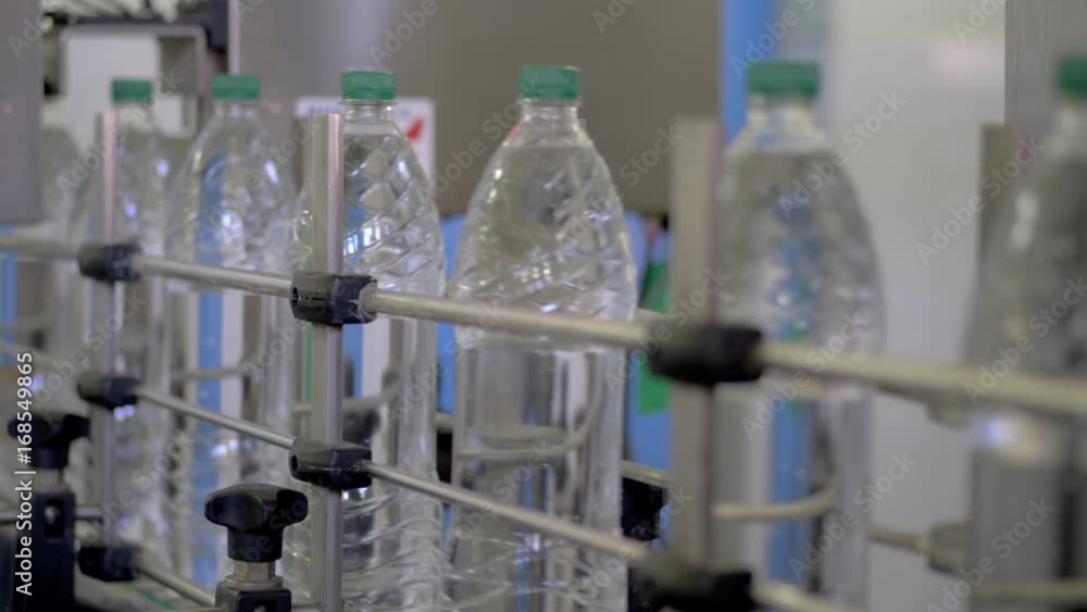 Automatic conveyor line for bottling mineral water in the plastic bottle. Line for PET bottle water. Water factory-bottling pure spring water into bottles. Selective focus. Automatic conveyor line for bottling mineral water in the plastic bottle. Line for PET bottle water. Water factory-bottling pure spring water into bottles. Selective focus.