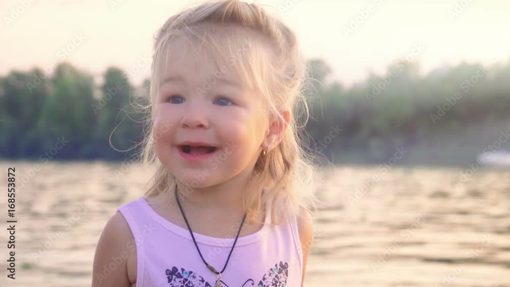 Portrait of a happy smiling little girl standing on the beach. Slow motion Portrait of a happy smiling little girl standing on the beach. Slow motion