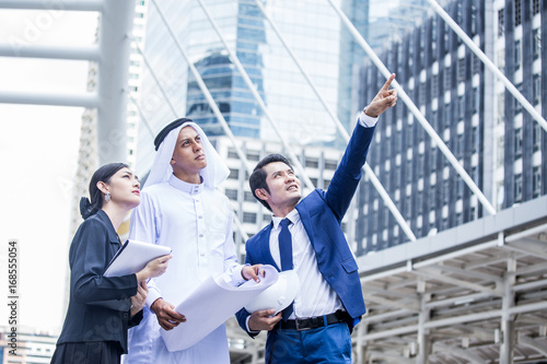 Businesspeople with Arab man Pointing to City for Work. People and Arab working concept. Arab man holding Blueprint and Thinking about Work.