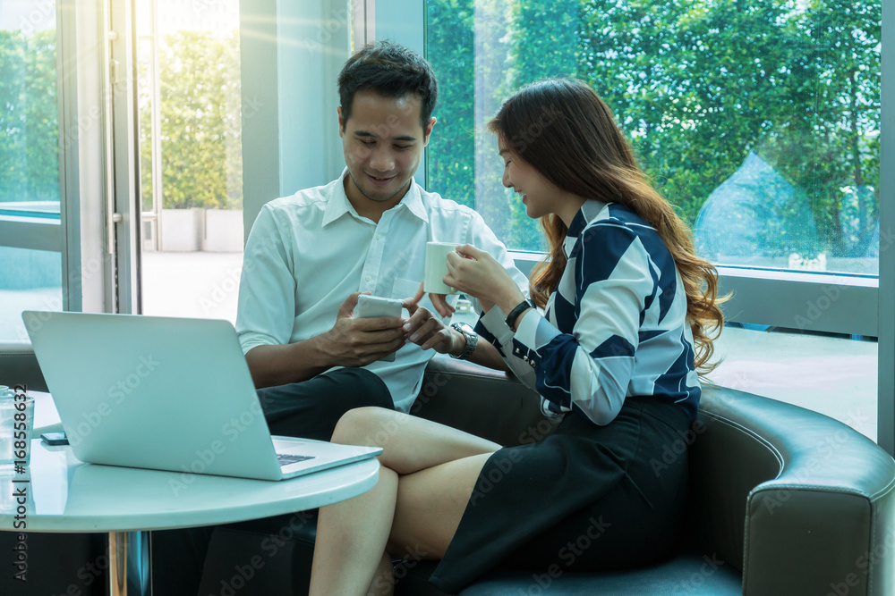 Happy Asian Beautiful young business woman and handsome businessman with formal suits are talking and using a laptop and smart phone for meeting in modern office, business people concept Happy Asian Beautiful young business woman and handsome businessman with formal suits are talking and using a laptop and smart phone for meeting in modern office, business people concept