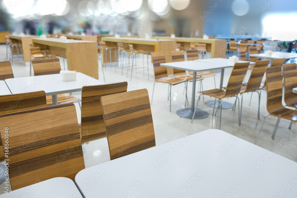 Interior of white table and wooden table on food court in shopping mall.
