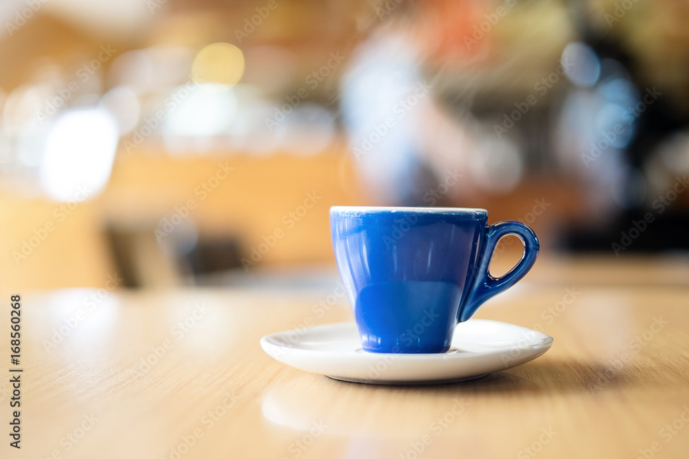 A blue cup of espresso coffee on wooden table in the background of cafeteria A blue cup of espresso coffee on wooden table in the background of cafeteria
