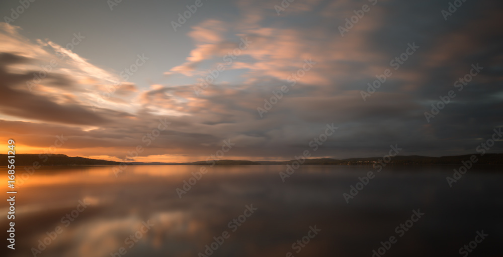 Fototapeta premium Beautiful sunset over a calm swedish natural lake in late summer photographed with long exposure