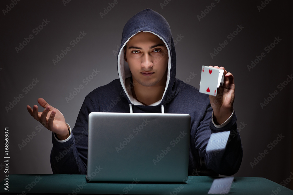 Young man wearing a hoodie sitting in front of a laptop computer Young man wearing a hoodie sitting in front of a laptop computer