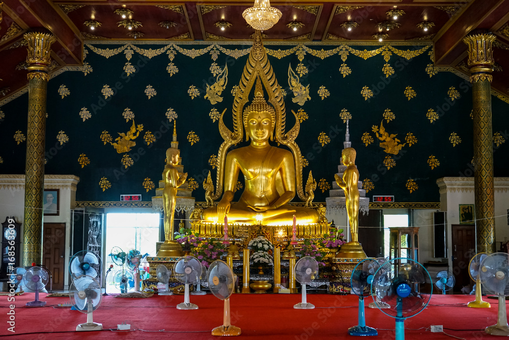 Principal buddha image in shinning golden color sitting in the decorative main hall with apostle monk image standing on both sides, Wat Asokaram